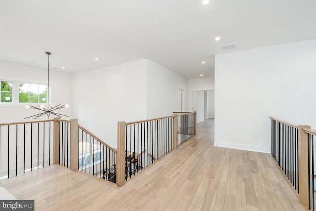 corridor featuring a notable chandelier and light hardwood / wood-style floors