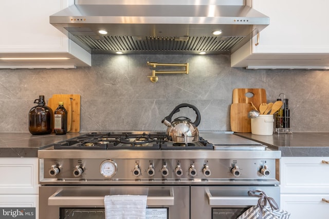 kitchen featuring white cabinetry, wall chimney exhaust hood, decorative backsplash, and high end range