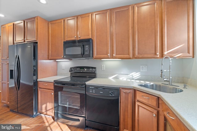 kitchen featuring sink, black appliances, and light hardwood / wood-style flooring