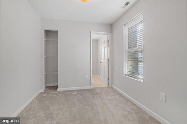 unfurnished bedroom featuring light colored carpet and a closet