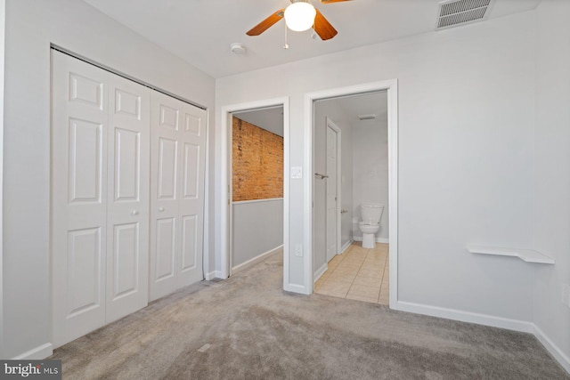 unfurnished bedroom featuring connected bathroom, light colored carpet, a closet, and ceiling fan