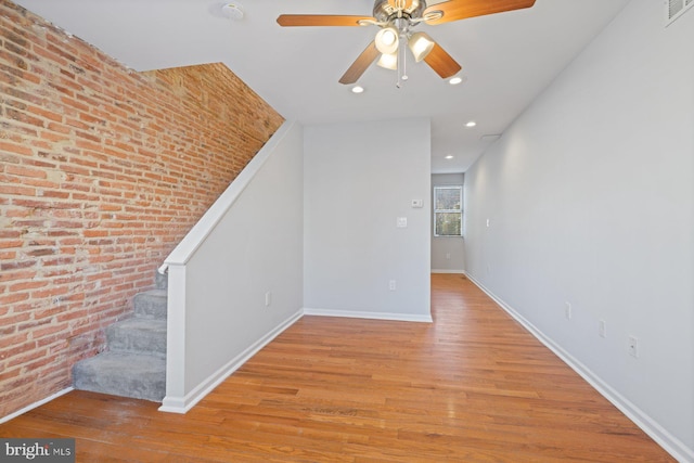 interior space featuring ceiling fan, brick wall, and light hardwood / wood-style flooring