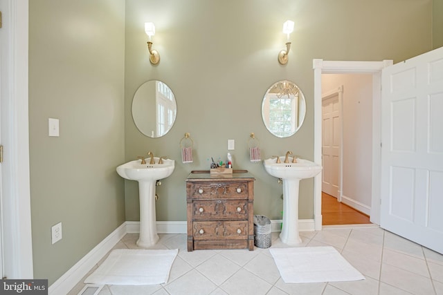 bathroom featuring tile patterned flooring, baseboards, and two sinks