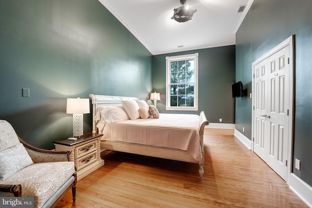 bedroom featuring ornamental molding, light wood-type flooring, visible vents, and baseboards