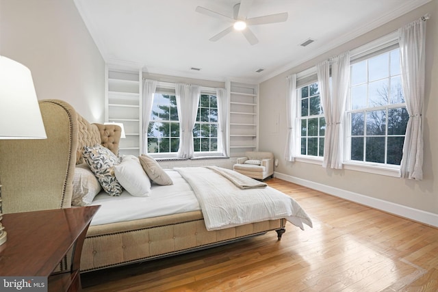 bedroom with baseboards, crown molding, visible vents, and wood finished floors