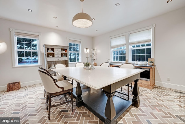 dining room featuring brick floor, plenty of natural light, and baseboards