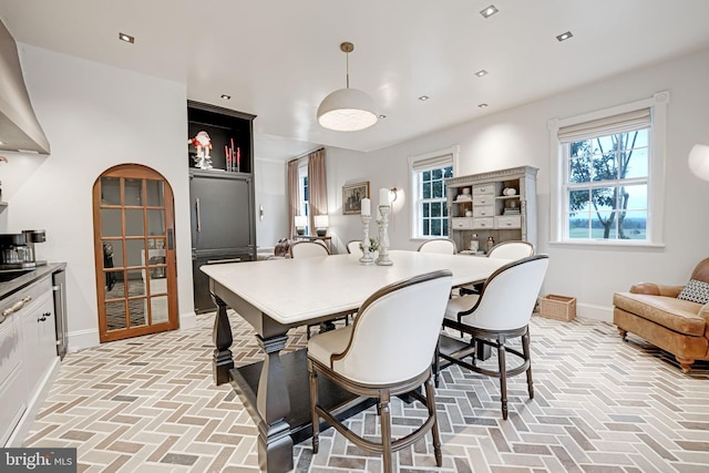 dining space featuring arched walkways, recessed lighting, brick floor, and baseboards