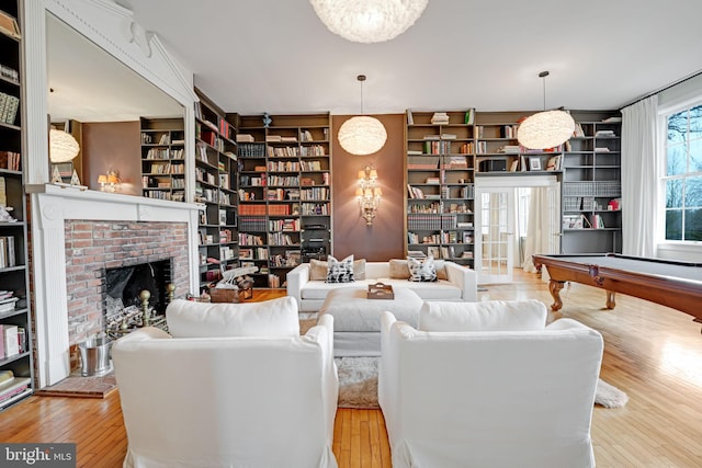 living room with hardwood / wood-style floors, a brick fireplace, and wall of books