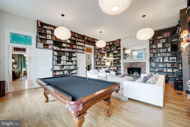 game room with a brick fireplace, wood-type flooring, built in features, and pool table