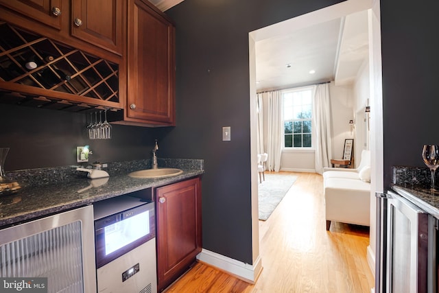 kitchen with light wood-style floors, beverage cooler, and a sink