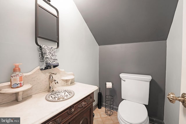 half bath with toilet, baseboards, and vanity