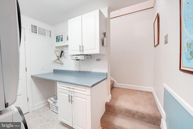 kitchen featuring baseboards, white cabinetry, visible vents, and built in desk