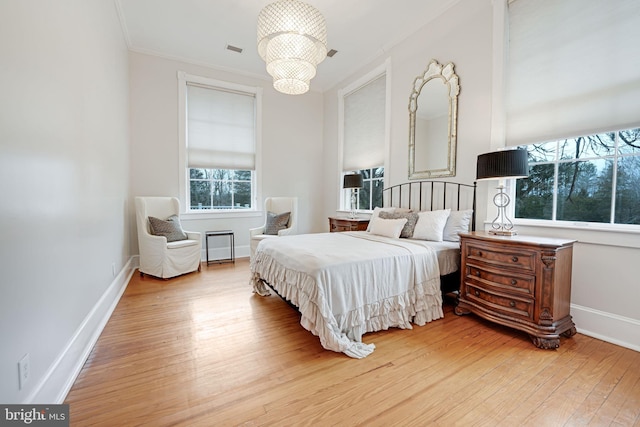 bedroom featuring wood-type flooring, visible vents, ornamental molding, a chandelier, and baseboards