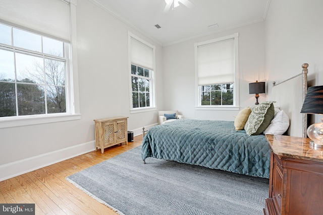 bedroom featuring visible vents, crown molding, baseboards, and wood finished floors