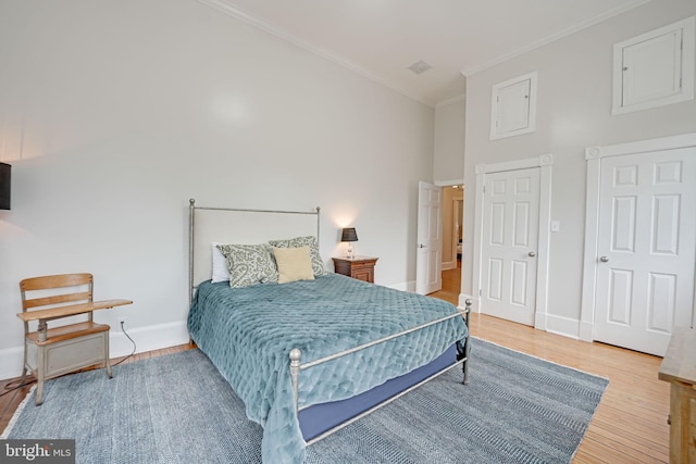 bedroom with baseboards, crown molding, and wood finished floors