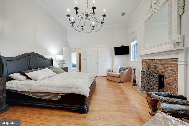 bedroom featuring light wood finished floors, ornamental molding, a closet, and a brick fireplace