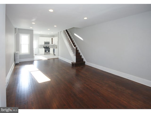 unfurnished living room with dark hardwood / wood-style flooring and radiator