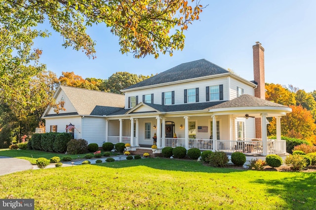 view of front facade featuring covered porch, a chimney, a shingled roof, and a front lawn