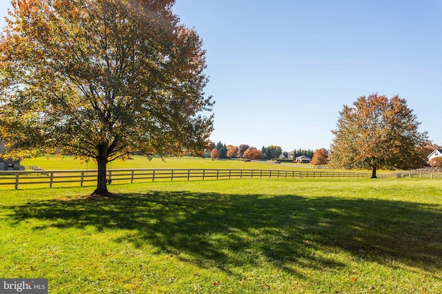 view of yard with fence and a rural view