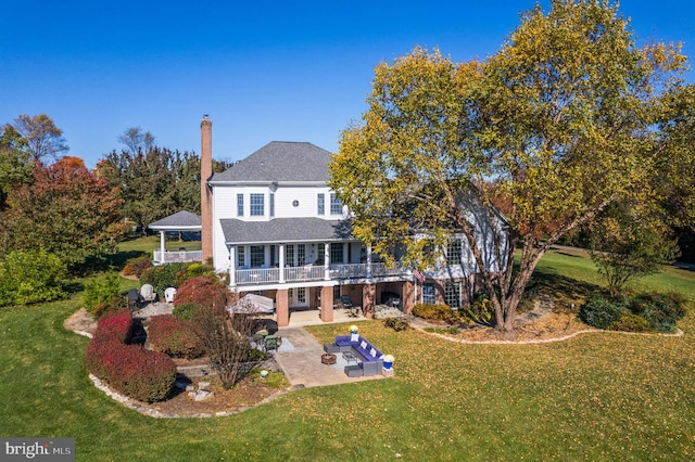 rear view of house featuring a patio, outdoor lounge area, a lawn, and a chimney