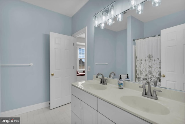 full bathroom with curtained shower, a sink, baseboards, and double vanity