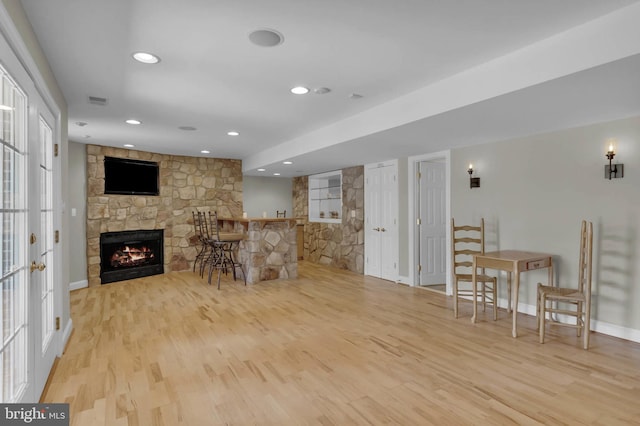 living room featuring recessed lighting, a fireplace, visible vents, baseboards, and light wood-type flooring