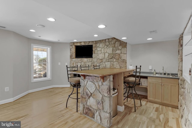 bar featuring indoor wet bar, visible vents, light wood-style flooring, a sink, and baseboards