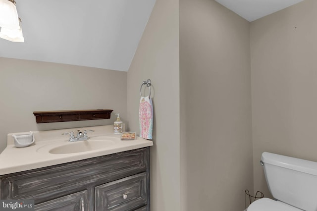 half bath featuring toilet, lofted ceiling, and vanity