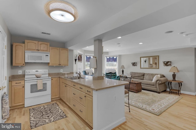 kitchen featuring light wood-style floors, open floor plan, light brown cabinets, a sink, and white appliances