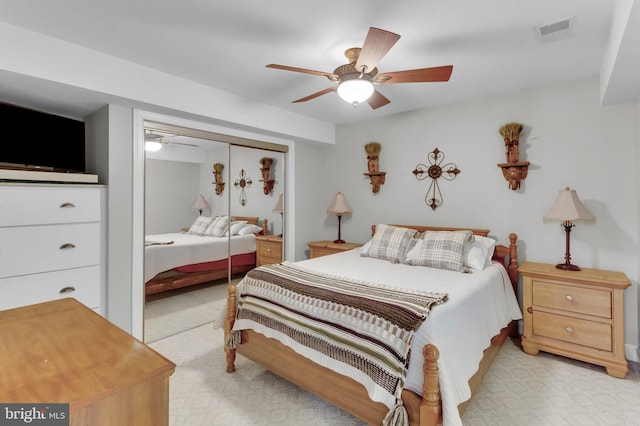 bedroom featuring ceiling fan, a closet, visible vents, and light colored carpet