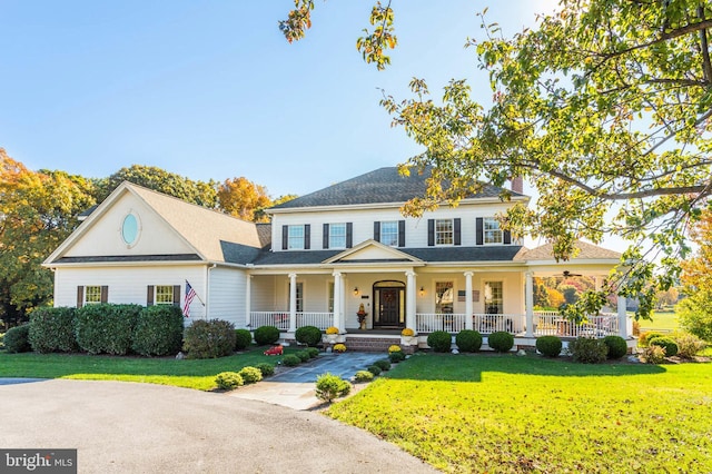 view of front of house with covered porch, a chimney, and a front yard