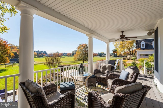 wooden terrace with fence, a porch, a ceiling fan, and a rural view