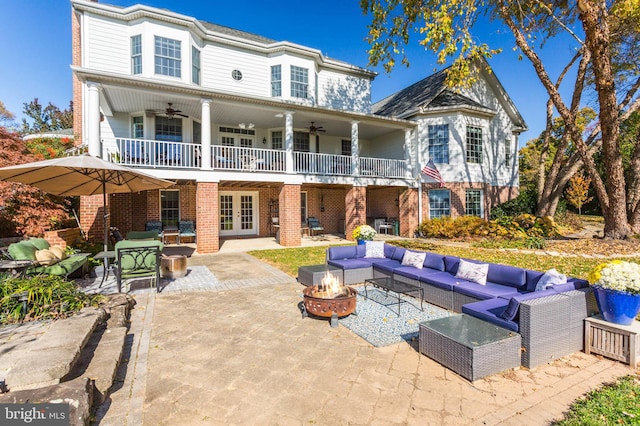 rear view of property featuring french doors, an outdoor living space with a fire pit, brick siding, and a patio