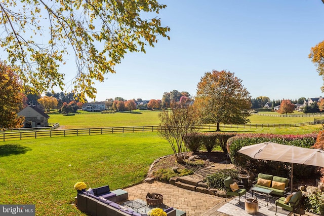 view of yard featuring a patio area, an outdoor fire pit, fence, and a rural view