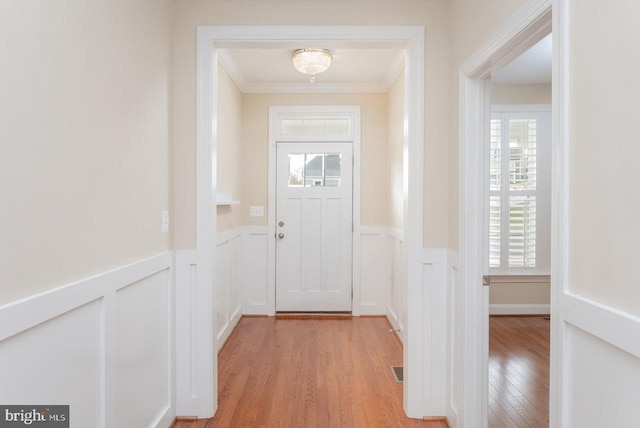 entryway featuring light wood-type flooring, ornamental molding, and plenty of natural light