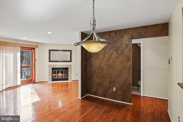 unfurnished dining area featuring a tiled fireplace and hardwood / wood-style floors