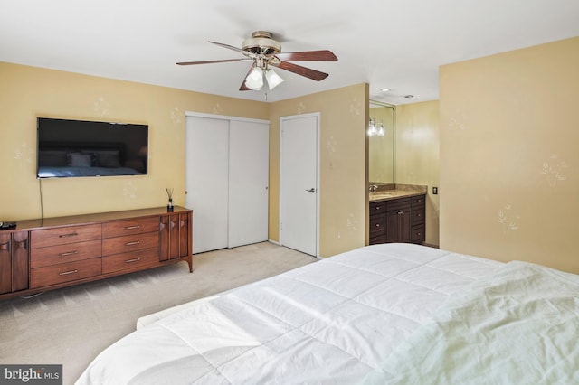 carpeted bedroom with ensuite bath, a closet, and ceiling fan