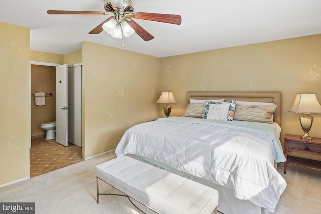 bedroom featuring connected bathroom, light colored carpet, and ceiling fan