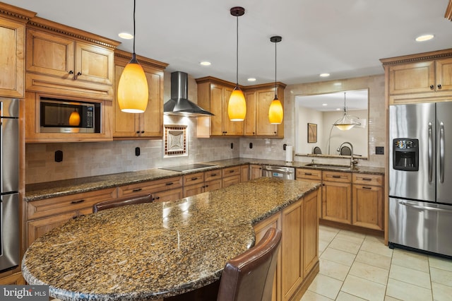 kitchen with sink, appliances with stainless steel finishes, a center island, decorative light fixtures, and wall chimney exhaust hood