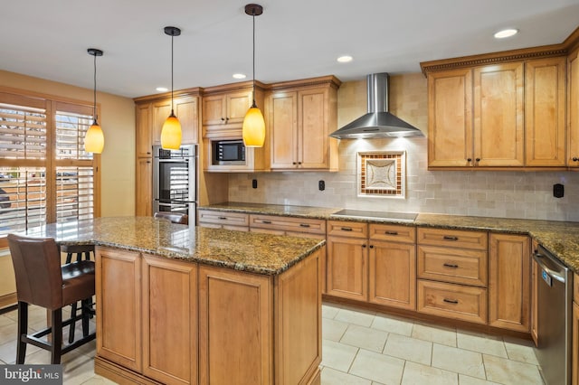 kitchen with stone counters, hanging light fixtures, a center island, stainless steel appliances, and wall chimney exhaust hood