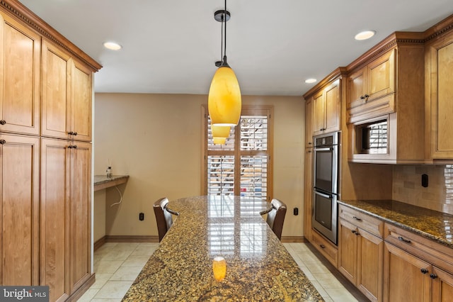 kitchen featuring light tile patterned floors, double oven, hanging light fixtures, tasteful backsplash, and dark stone counters