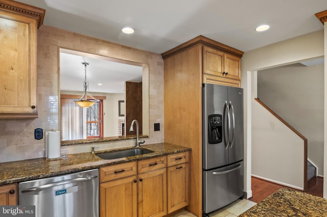 kitchen with tasteful backsplash, stainless steel appliances, sink, and dark stone counters