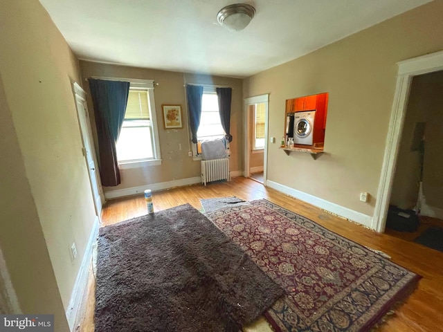 interior space featuring washer / dryer, light hardwood / wood-style flooring, and radiator heating unit