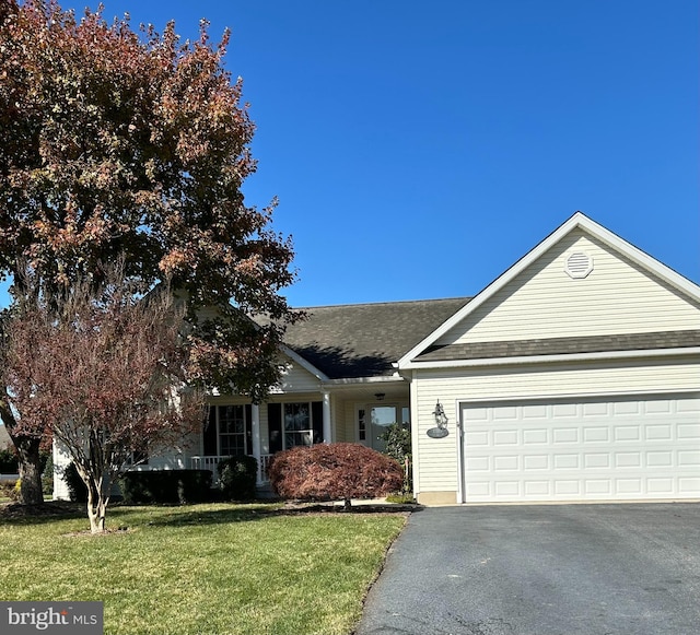 view of front of property featuring aphalt driveway, a garage, a shingled roof, and a front yard