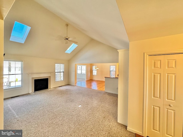 unfurnished living room with ceiling fan, a healthy amount of sunlight, light carpet, and vaulted ceiling