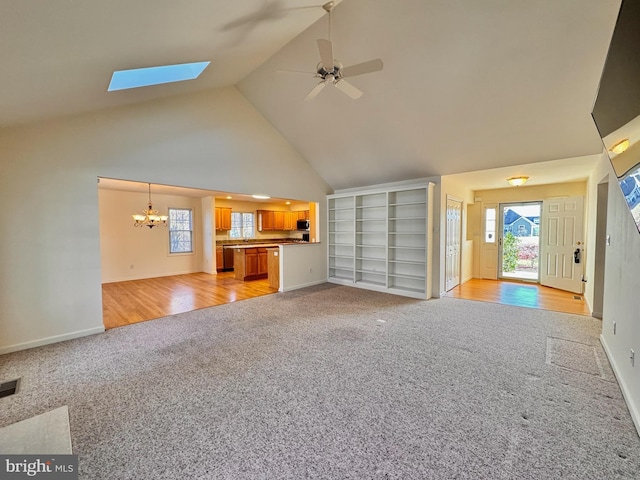 unfurnished living room featuring ceiling fan with notable chandelier, light hardwood / wood-style floors, and high vaulted ceiling