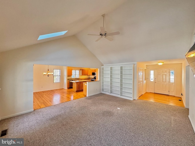 unfurnished living room with high vaulted ceiling, ceiling fan with notable chandelier, and light wood-type flooring