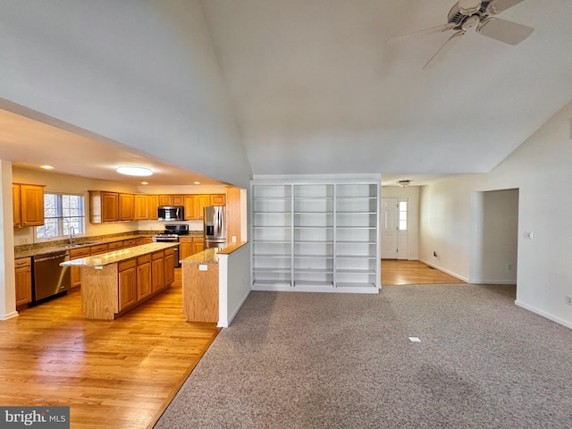 kitchen with appliances with stainless steel finishes, vaulted ceiling, ceiling fan, light hardwood / wood-style floors, and a kitchen island