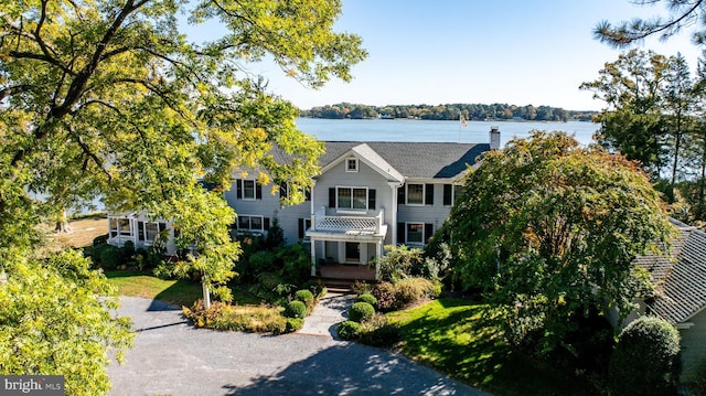 view of front facade featuring a front yard, a water view, and a chimney