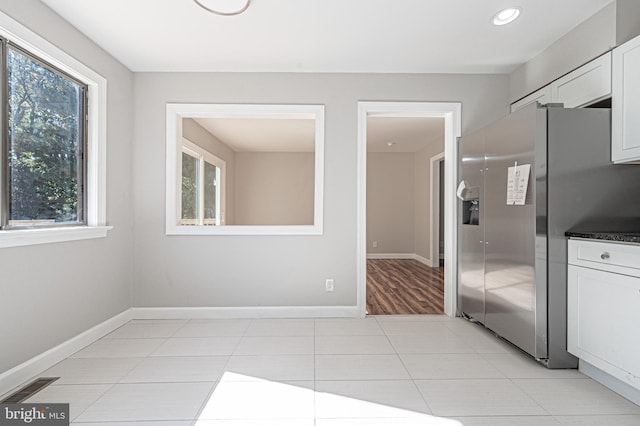 kitchen featuring white cabinetry, light tile patterned flooring, and stainless steel fridge with ice dispenser